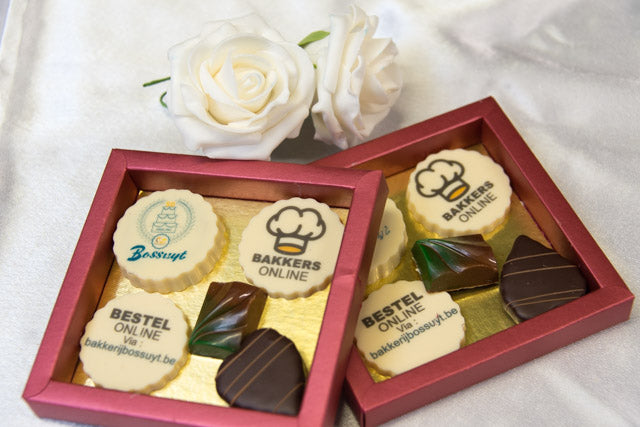 Een geschenkdoos met pralines en chocoladeschijfjes met een logo in eetbare inkt