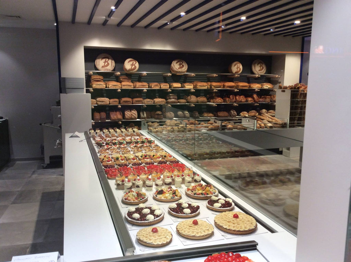 Toonbank vol gebak en rekken met vers brood in de winkel van Bakkerij Bossuyt op het Kristus Koningplein in Ekeren