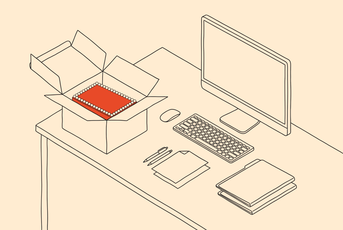 A desk with a computer screen and an open box with the cake inside.
