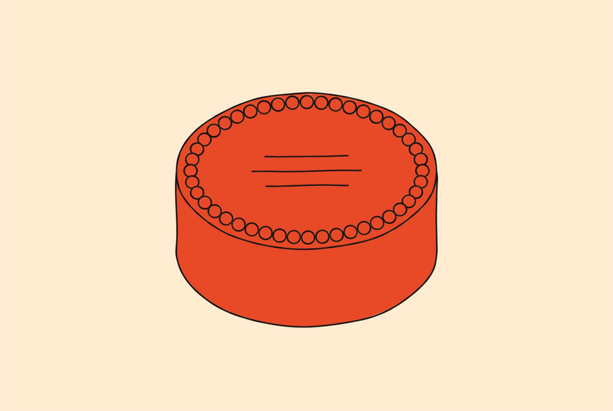 Een lage ronde cake van schuin boven, met een ring glazuurdotjes langs de rand en de gedrukte boodschap op het bovenvlak.